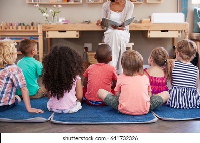 Teacher At Montessori School Reading To Children At Story Time