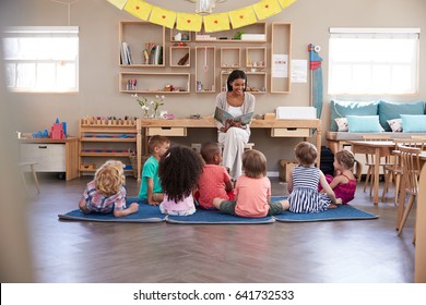 Teacher At Montessori School Reading To Children At Story Time