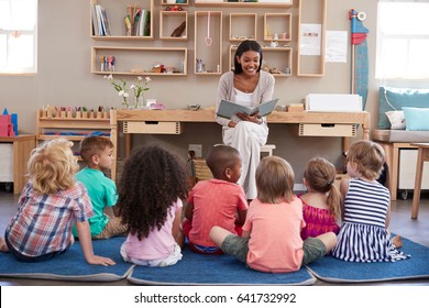 Teacher At Montessori School Reading To Children At Story Time