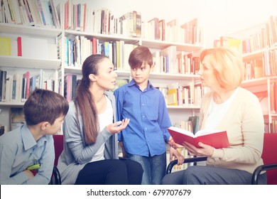 Teacher and mother with sons on meeting at school library