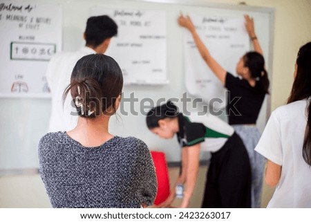 A teacher observes her students as they prepare for a class reporting.