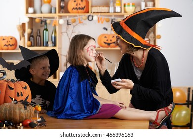 Teacher Painting Face Of Little Girl For Halloween Celebration