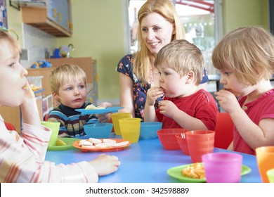 Teacher With Pre School Children Eating Healthy Snacks At Breakt