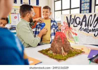 Teacher presenting award badge to schoolboy for volcano anatomy explanation in primary school. Excited little boy explaining volcanic eruption using model  after winning a science competition. - Powered by Shutterstock