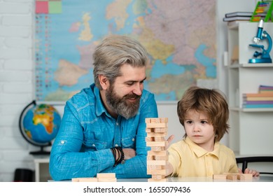 Teacher And Pupil. Elementary School Tutorship. School Community Partnership Models. Happy Father And Focused Son Playing Jenga Game At Home