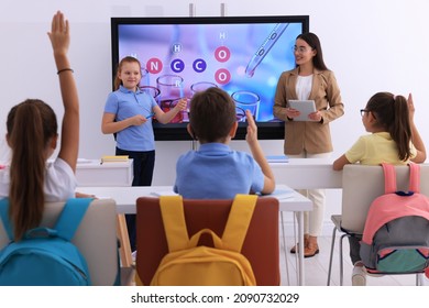 Teacher And Pupil Using Interactive Board In Classroom During Lesson