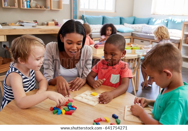 Teacher And Pupils Using Wooden Shapes In\
Montessori School