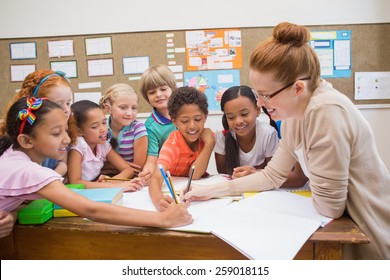 Teacher and pupils working at desk together at the elementary school - Powered by Shutterstock