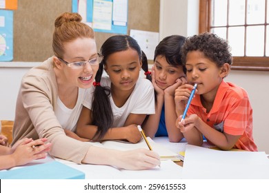 Teacher and pupils working at desk together at the elementary school