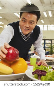 Teacher Reaching For Healthy Food In School Cafeteria