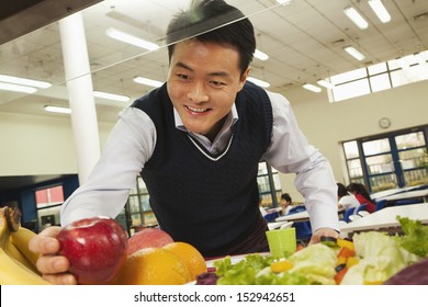 Teacher Reaching For Healthy Food In School Cafeteria