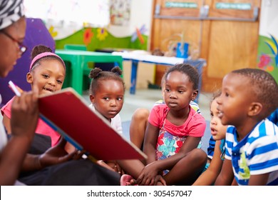 Teacher reading a book with a class of preschool children - Shutterstock ID 305457047