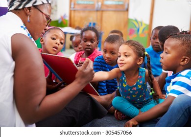 Teacher reading a book with a class of preschool children - Shutterstock ID 305457056