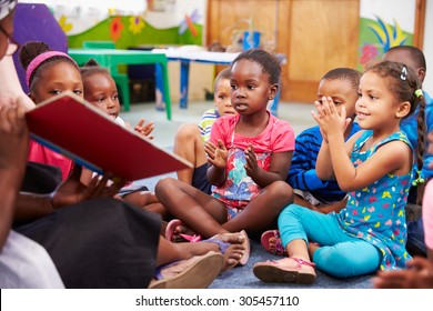 Teacher reading a book with a class of preschool children - Shutterstock ID 305457110