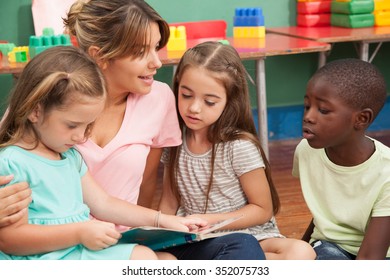 Teacher reading a book to her kindergarten class - Shutterstock ID 352075733
