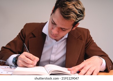 A Teacher Reviewing Papers In The Classroom. Business Man Dressed In Cafe Suit Signing Important Papers. Man Working In His Office. A Sales Executive Reading His Black Pad.