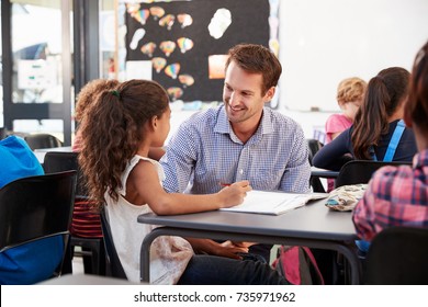 Teacher and schoolgirl at her desk, looking at each other