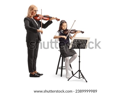Teacher and a schoolgirl sitting on a chair and playing a violin isolated on white background