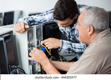 Teacher And Senior Man Fixing Computer In Class