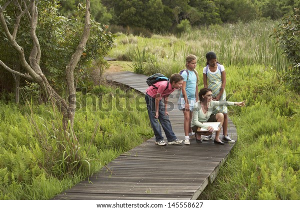 Teacher showing something to children during nature\
field trip