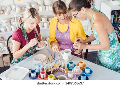 Teacher showing two women in workshop how to paint self-made dishes - Powered by Shutterstock