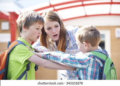 Teacher Stopping Two Boys Fighting In Playground
