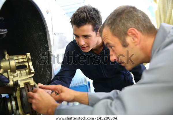 Teacher and\
student in auto mechanics training\
class