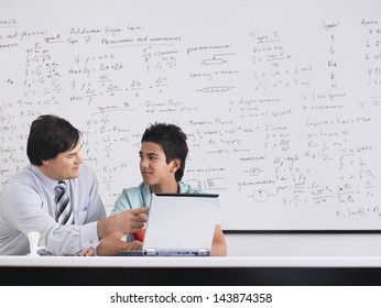 Teacher And Student Using Laptop Sitting In Physics Classroom