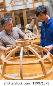 Teacher And Student At A Workbench In A Woodworking Class Working On A Frame