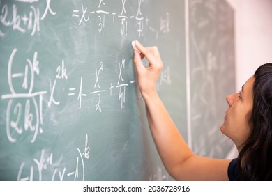 Teacher or student writing on blackboard during math lesson in school classroom.