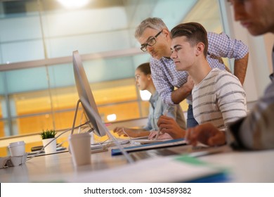 Teacher with students in apprenticeship attending computing class