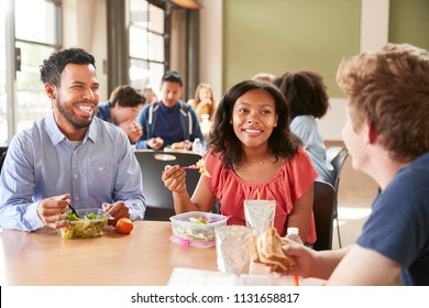 Teacher And Students Eating Lunch In High School Cafeteria During Recess