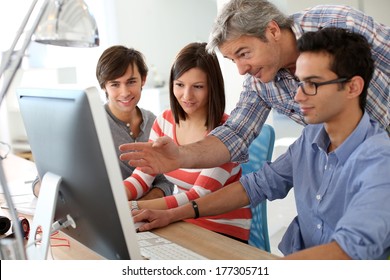 Teacher with students working on desktop 
