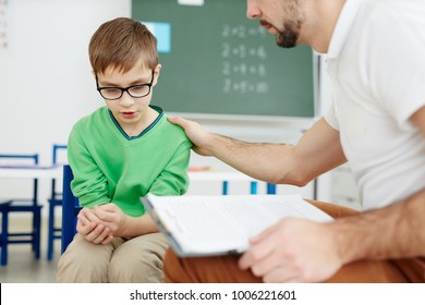 Teacher Supporting Upset Or Confused Schoolboy During Individual Lesson