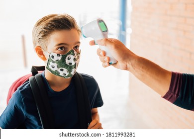 Teacher Taking A Boy Temperature With A Thermometer During Covid Pandemic. 