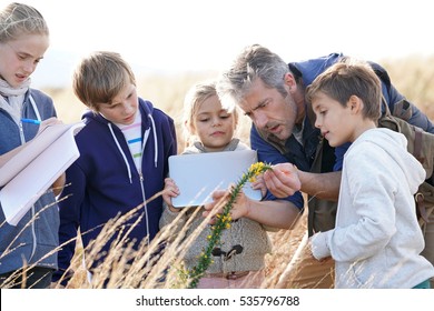 Teacher Taking Kids To Countryside To Explore Plants And Flowers 