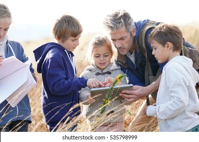 Teacher taking kids to countryside to explore plants and flowers  - Powered by Shutterstock