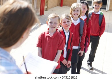 Teacher Taking School Register In Playground