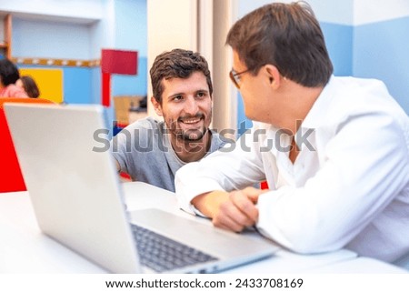 Teacher talking to a man with down syndrome during computing class