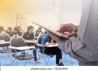 Teacher Teach Students And Background Of Students During Study Or Quiz, Test And Exams In Large Lecture Room / University Classroom. Students Are In Uniform Classroom Educational School.