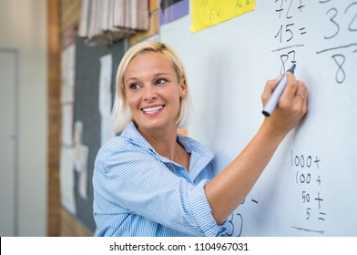 Teacher teaching how to count on whiteboard in classroom. Smiling blonde woman explaining additions in column in class. Math’s teacher explaining arithmetic sums to elementary children. - Shutterstock ID 1104967031
