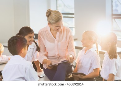Teacher Teaching Kids On Digital Tablet In Classroom At School