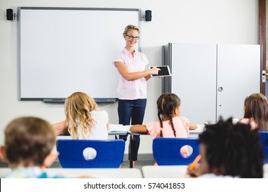 Teacher Teaching Kids On Digital Tablet In Classroom At School