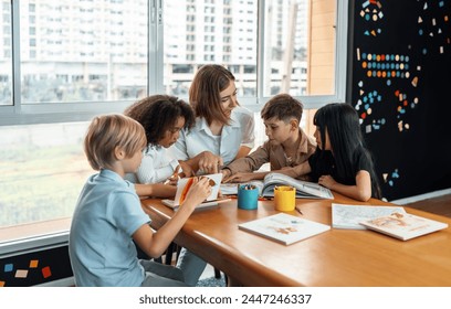 Teacher is teaching student about lesson from the books in the classroom, the children are happy. Some ask teacher, a boy in blue shirt is reading a book on his own and a girl is drawing. Erudition. - Powered by Shutterstock