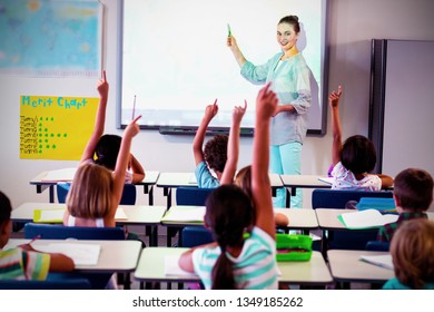 Teacher Teaching Students Using Projector In Classroom At School