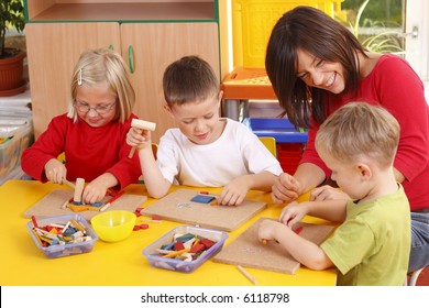 teacher and three preschoolers playing with wooden blocks - Shutterstock ID 6118798