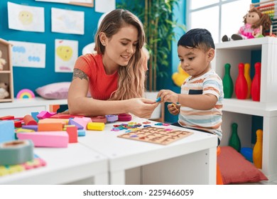 Teacher and toddler playing with maths puzzle game sitting on table at kindergarten - Shutterstock ID 2259466059