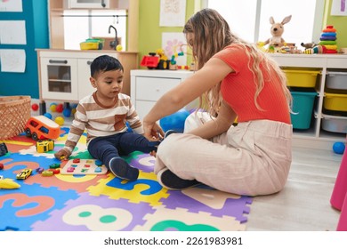 Teacher and toddler tying shoe at kindergarten