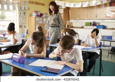 Teacher Walking In Her Busy Primary School Classroom