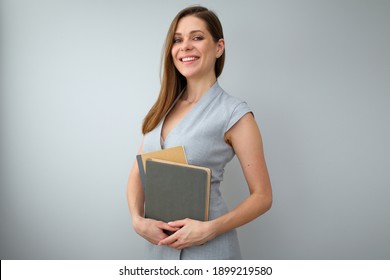 Teacher Wearing Grey Dress, Holding Work Books And Looking Straight. Isolated Female Portrait.